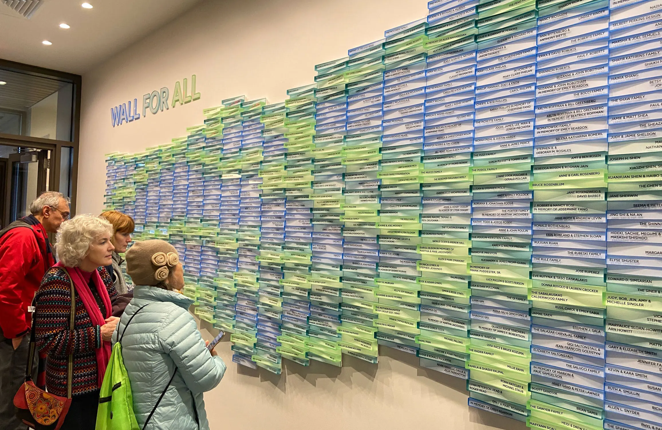 Visitors viewing the colorful donor wall at the Belmont Public Library